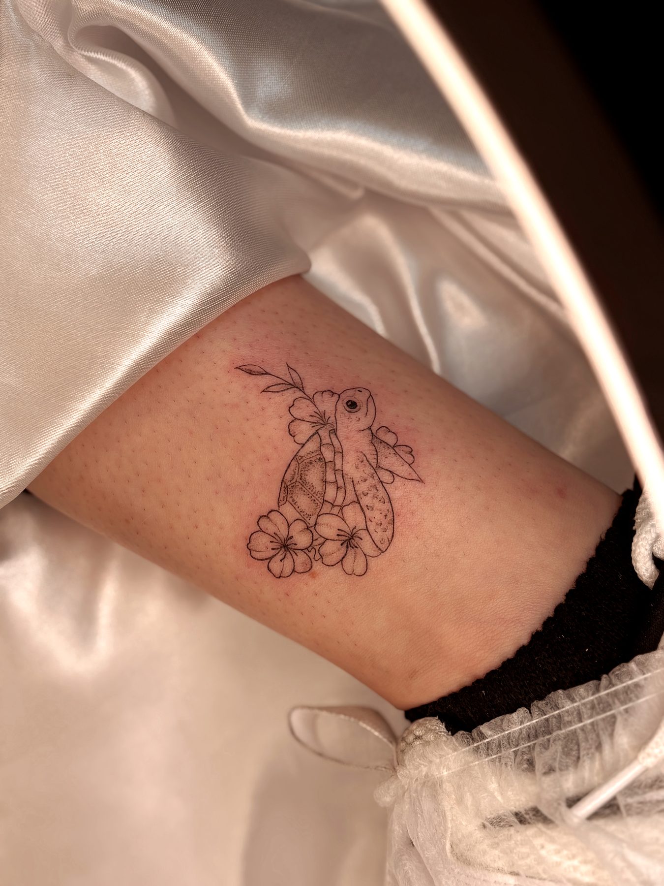 Tatuagem fineline de tartaruga com flores