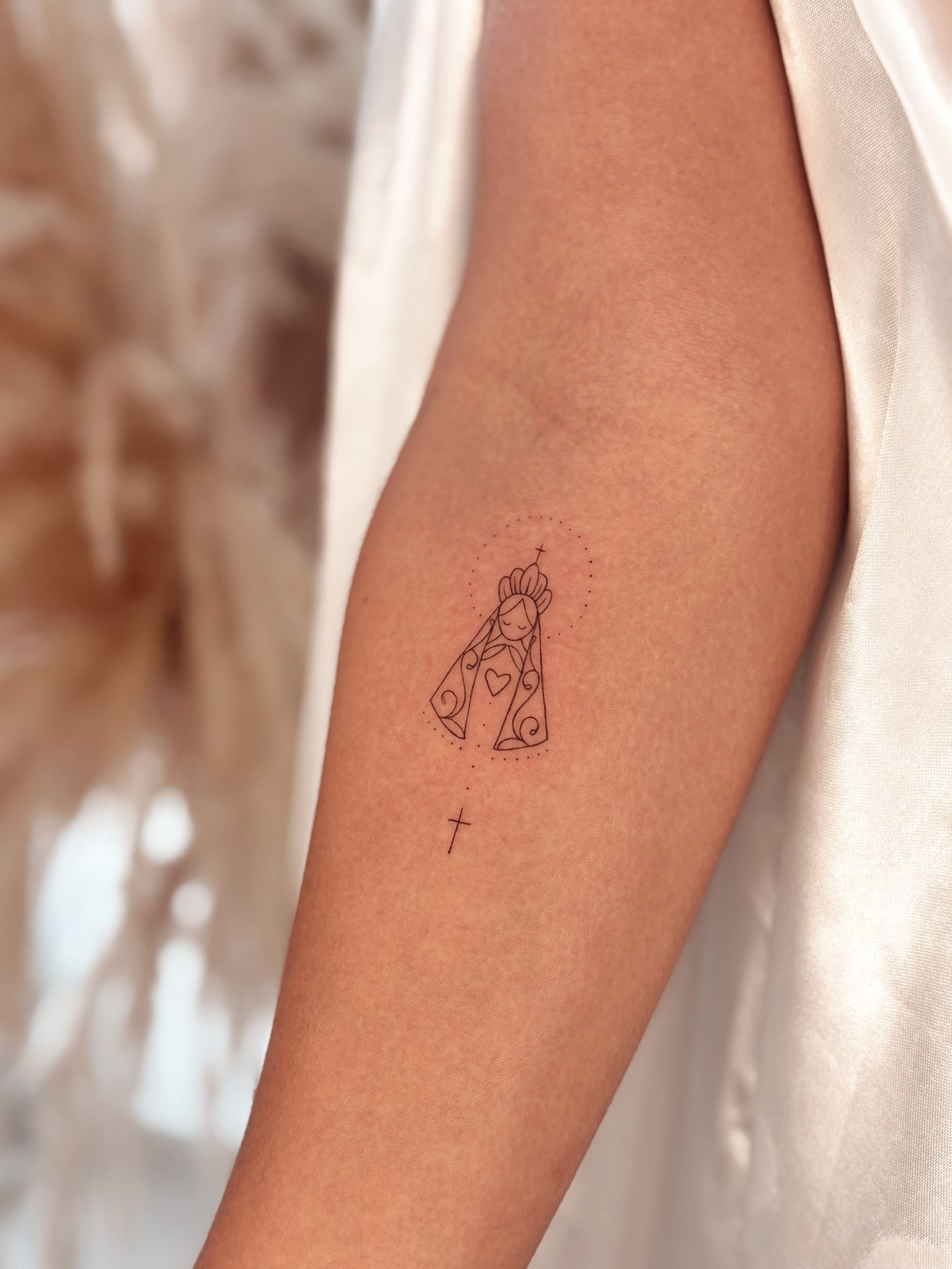 Tatuagem fineline de Nossa Senhora no braço